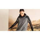 Model in grey textured cowl neck dress with sheer black sleeves against desert landscape backdrop