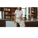 Woman in white tee and beige midi skirt seated on counter in warm library setting